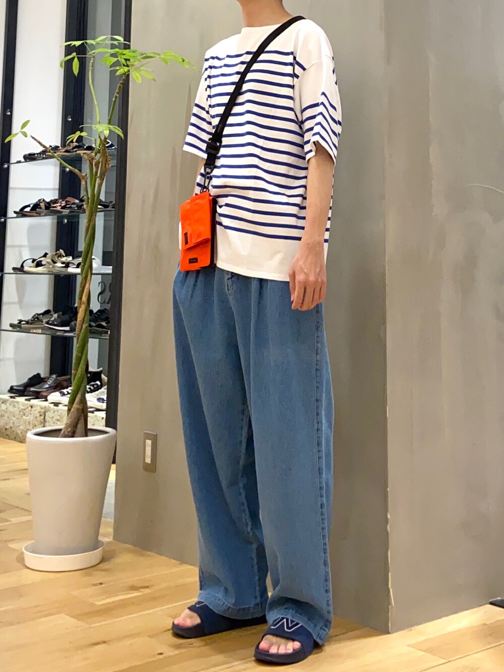 ブルー系のTシャツ/カットソー、オレンジ系のショルダーバッグ、ブルー系のデニムパンツを着用したメンズの夏コーディネートの2枚目の写真