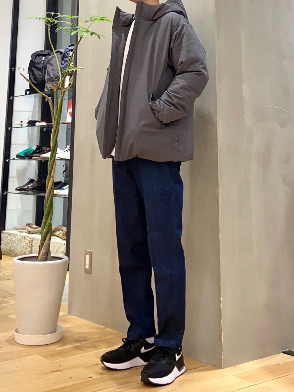 グレー系のダウンジャケット/コート、ベージュ系のシャツ/ブラウス、ブルー系のデニムパンツを着用したメンズの冬コーディネートの3枚目の写真