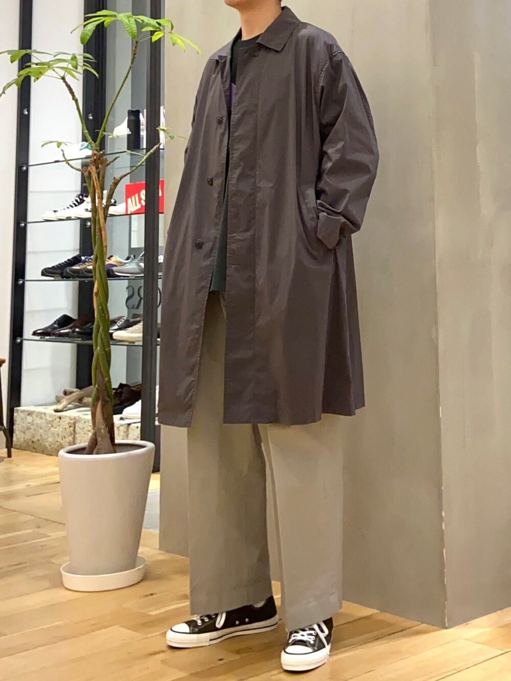 グレー系のステンカラーコート、グリーン系のTシャツ/カットソー、グレー系のその他パンツを着用したメンズの春コーディネートの2枚目の写真
