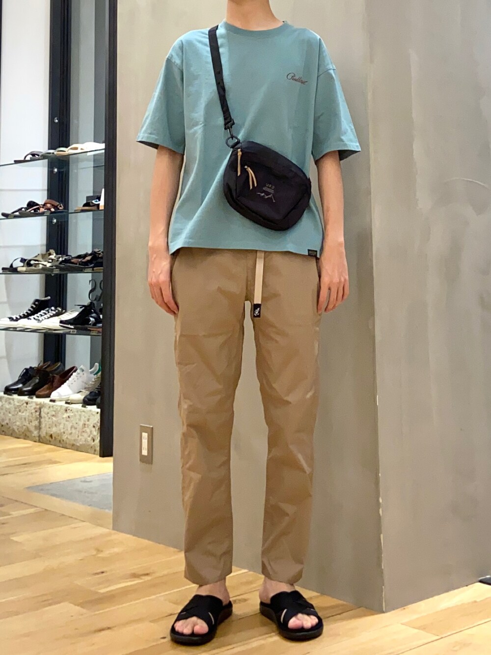 グリーン系のTシャツ/カットソー、ブラック系のショルダーバッグ、ベージュ系のその他パンツを着用したメンズの春コーディネートの2枚目の写真