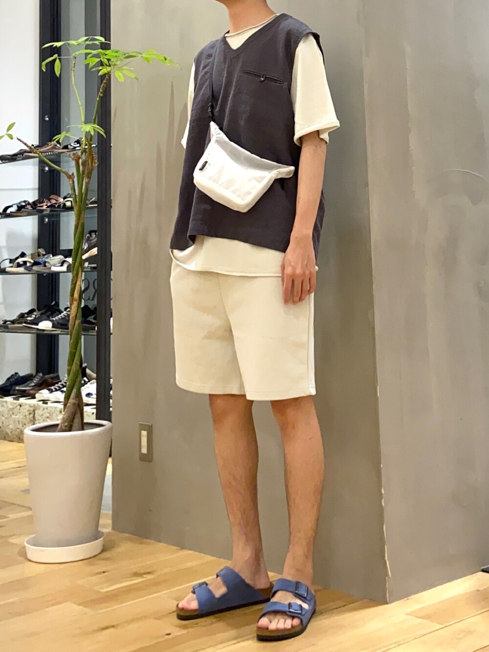 ブラック系のベスト、ホワイト系のショルダーバッグ、ブルー系のサンダルを着用したメンズの夏コーディネートの2枚目の写真