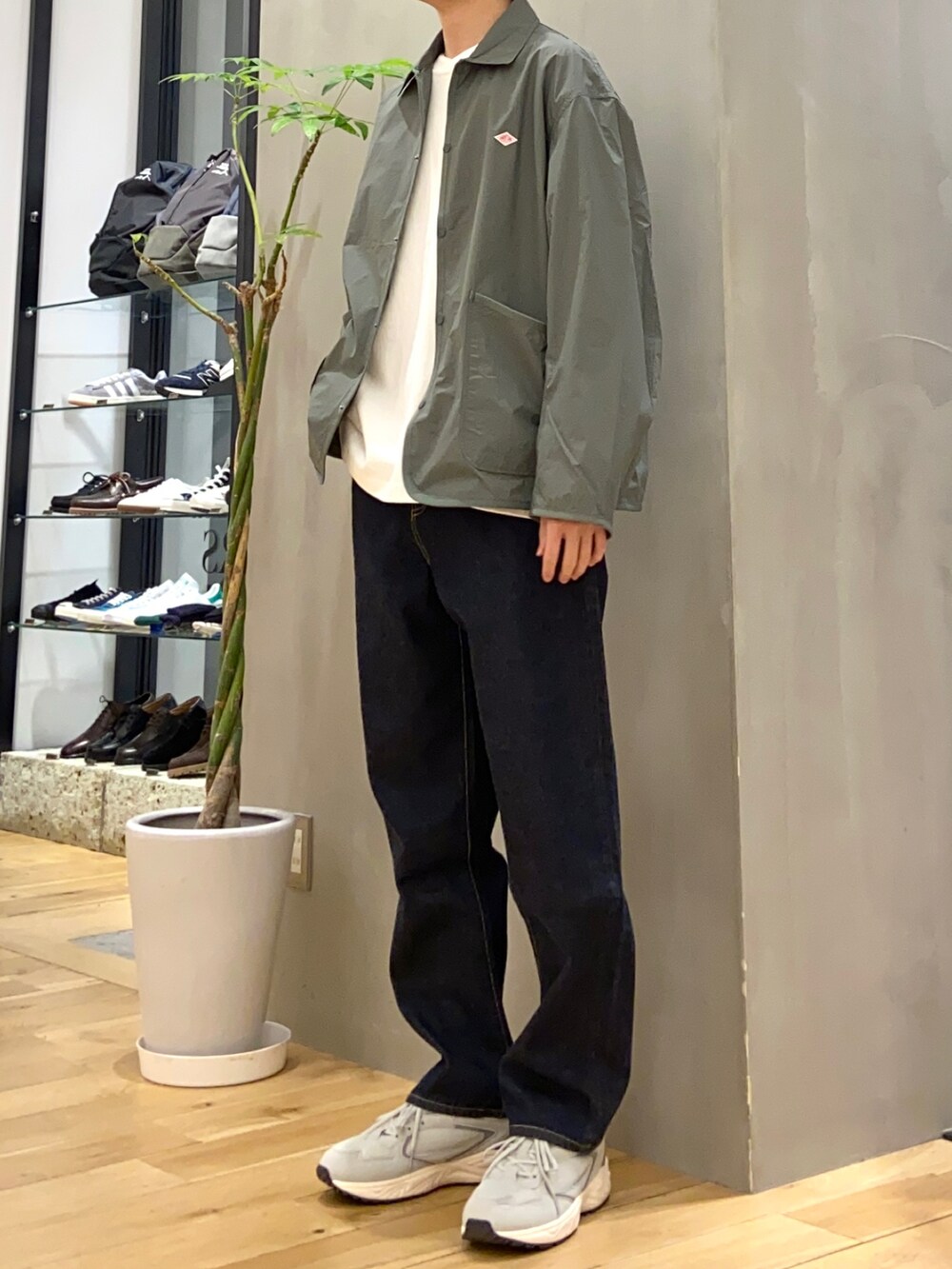 グリーン系のナイロンジャケット、ブルー系のデニムパンツ、グレー系のスニーカーを着用したメンズの春コーディネートの3枚目の写真