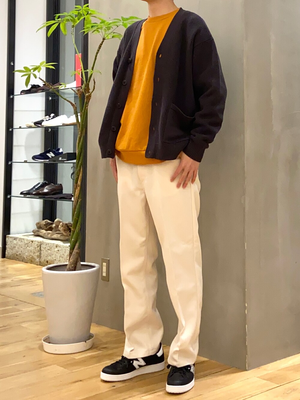 グレー系のカーディガン/ボレロ、オレンジ系のTシャツ/カットソー、ブラック系のスニーカーを着用したメンズの冬コーディネートの4枚目の写真