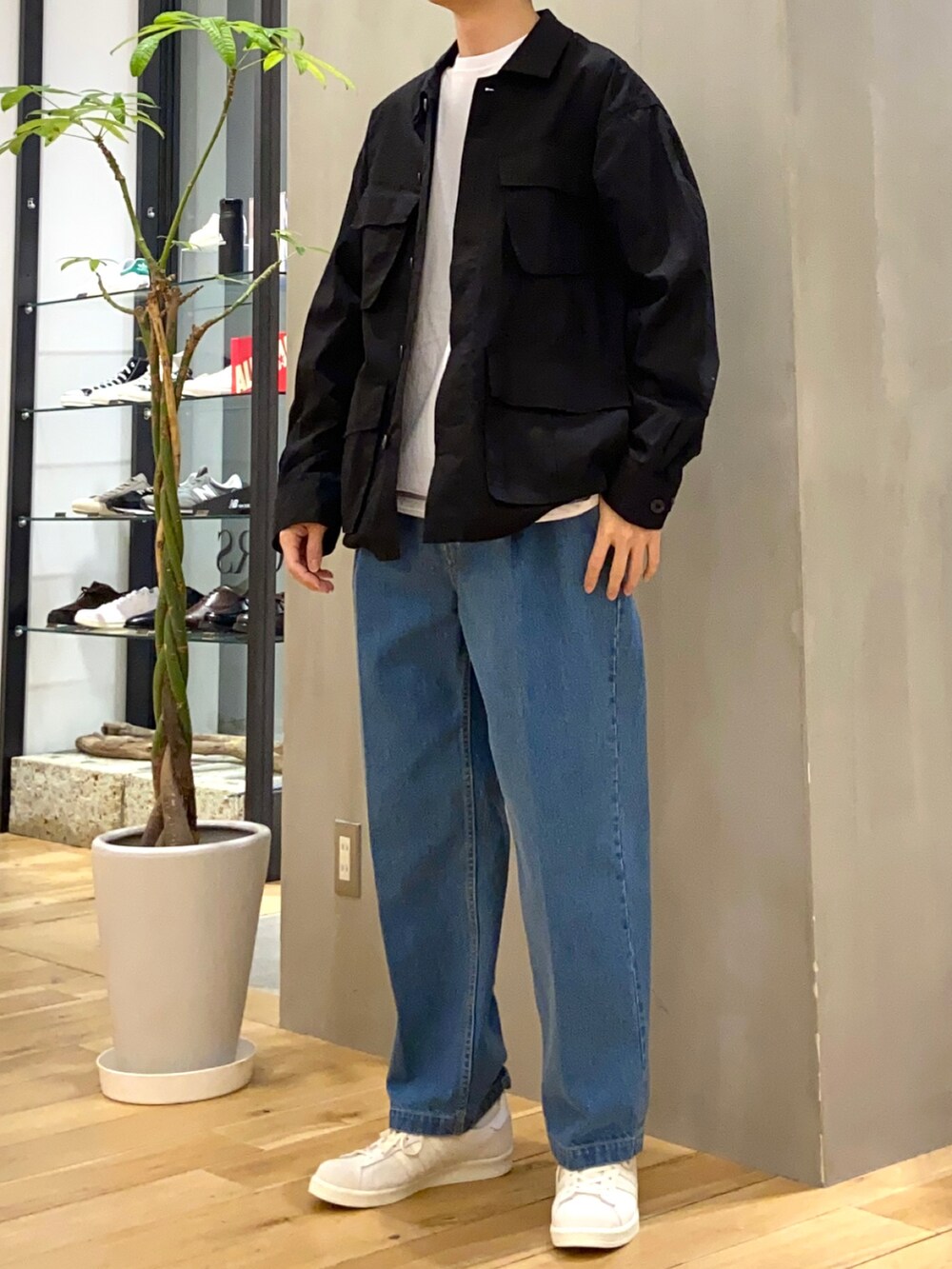 ブラック系のミリタリージャケット、ブルー系のデニムパンツ、ベージュ系のスニーカーを着用したメンズの春コーディネートの3枚目の写真