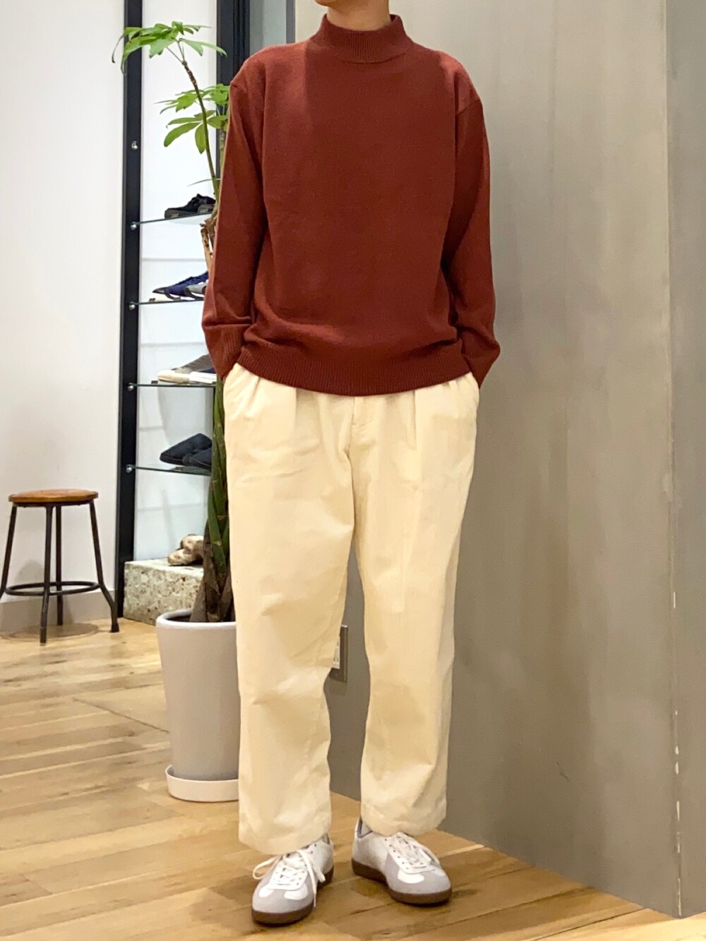 ブラック系のステンカラーコート、レッド系のニット/セーター、ホワイト系のその他パンツを着用したメンズの秋コーディネートの2枚目の写真
