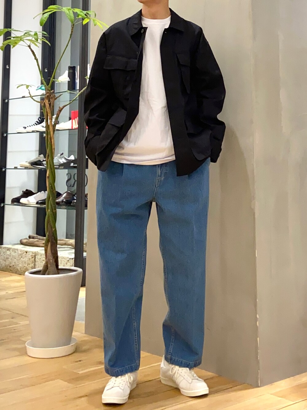 ブラック系のミリタリージャケット、ブルー系のデニムパンツ、ベージュ系のスニーカーを着用したメンズの春コーディネートの4枚目の写真