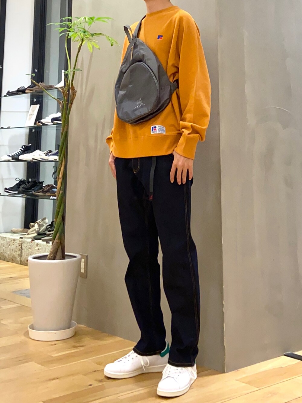 オレンジ系のスウェット、グレー系のショルダーバッグ、ブルー系のその他パンツを着用したメンズの秋コーディネートの2枚目の写真