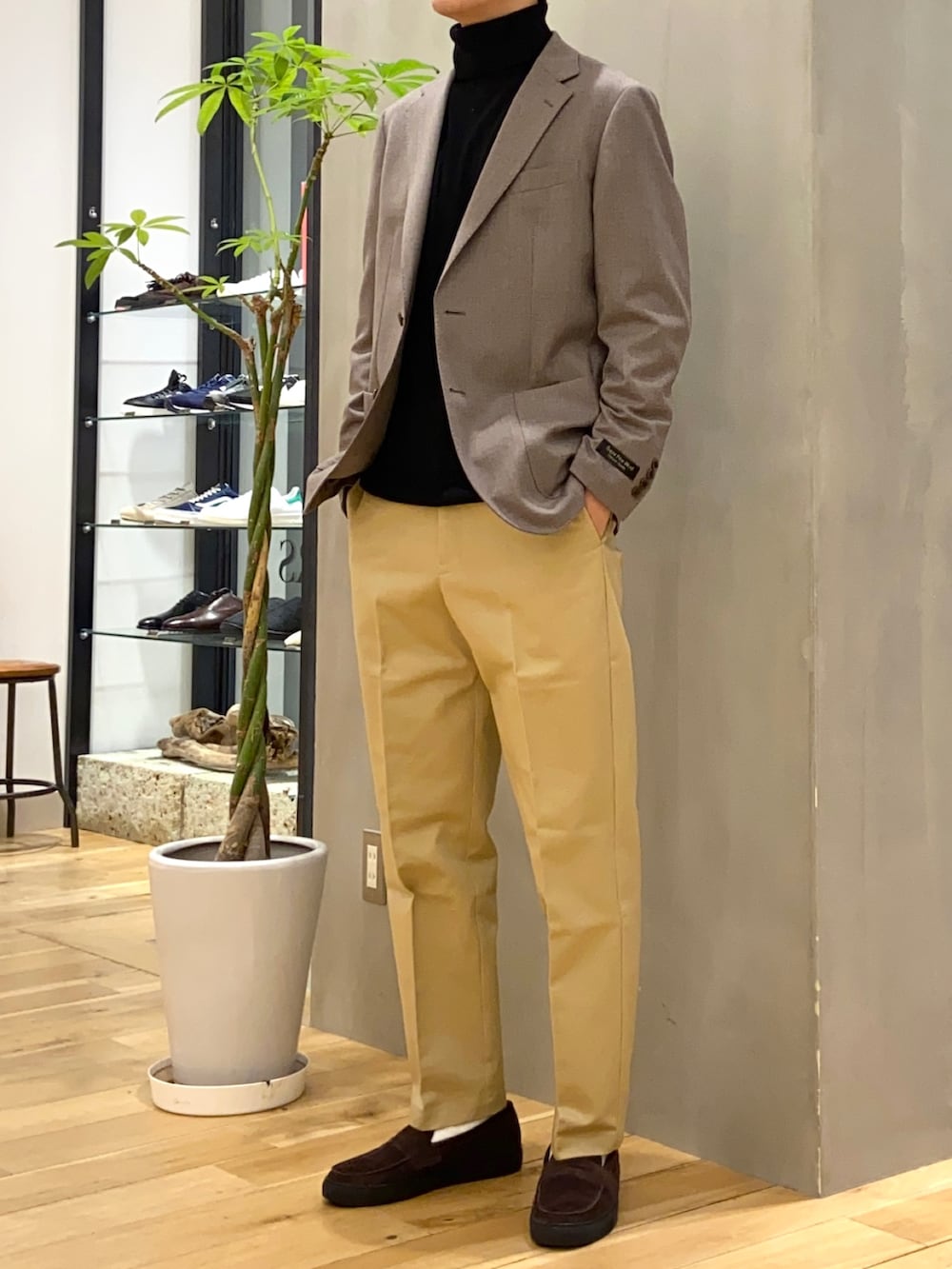 ブラウン系のスーツジャケット、ブラック系のニット/セーター、ブラウン系のローファーを着用したメンズの冬コーディネートの2枚目の写真