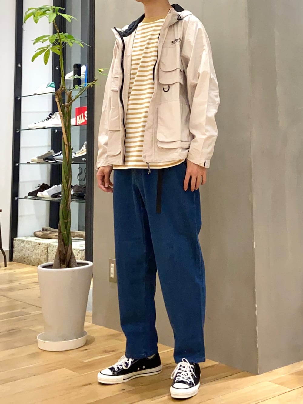 ベージュ系のマウンテンパーカー、イエロー系のTシャツ/カットソー、ブルー系のデニムパンツを着用したメンズの春コーディネートの2枚目の写真