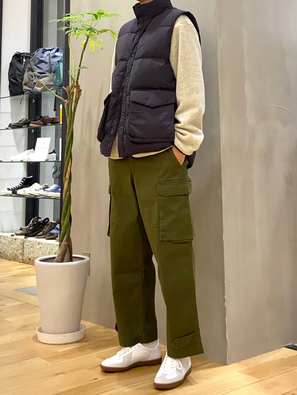 ブラック系のダウンベスト、グリーン系のカーゴパンツ、ホワイト系のスニーカーを着用したメンズの秋コーディネートの2枚目の写真