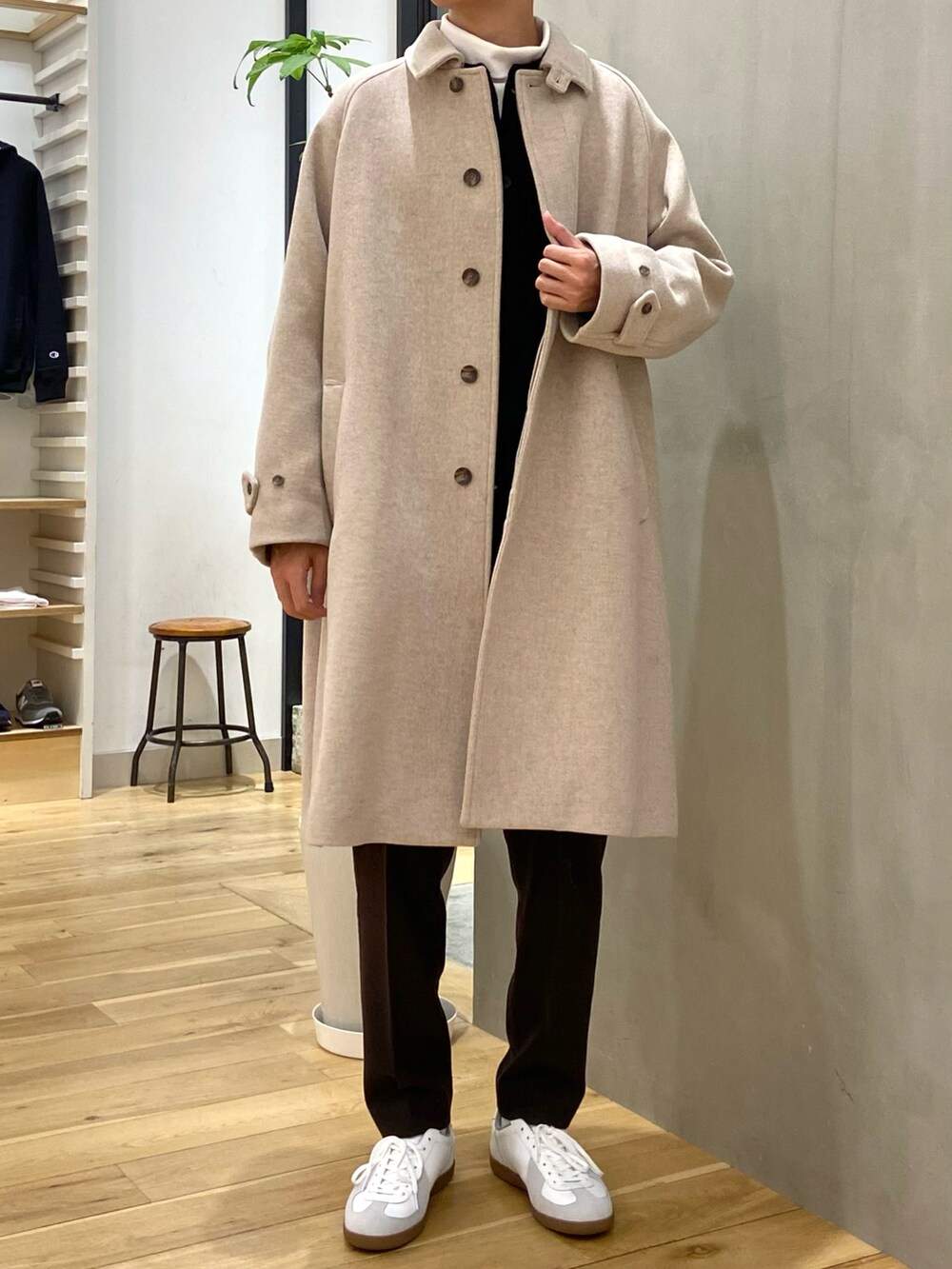 ホワイト系のステンカラーコート、ブラック系のカーディガン/ボレロ、ホワイト系のTシャツ/カットソーを着用したメンズの冬コーディネートの3枚目の写真