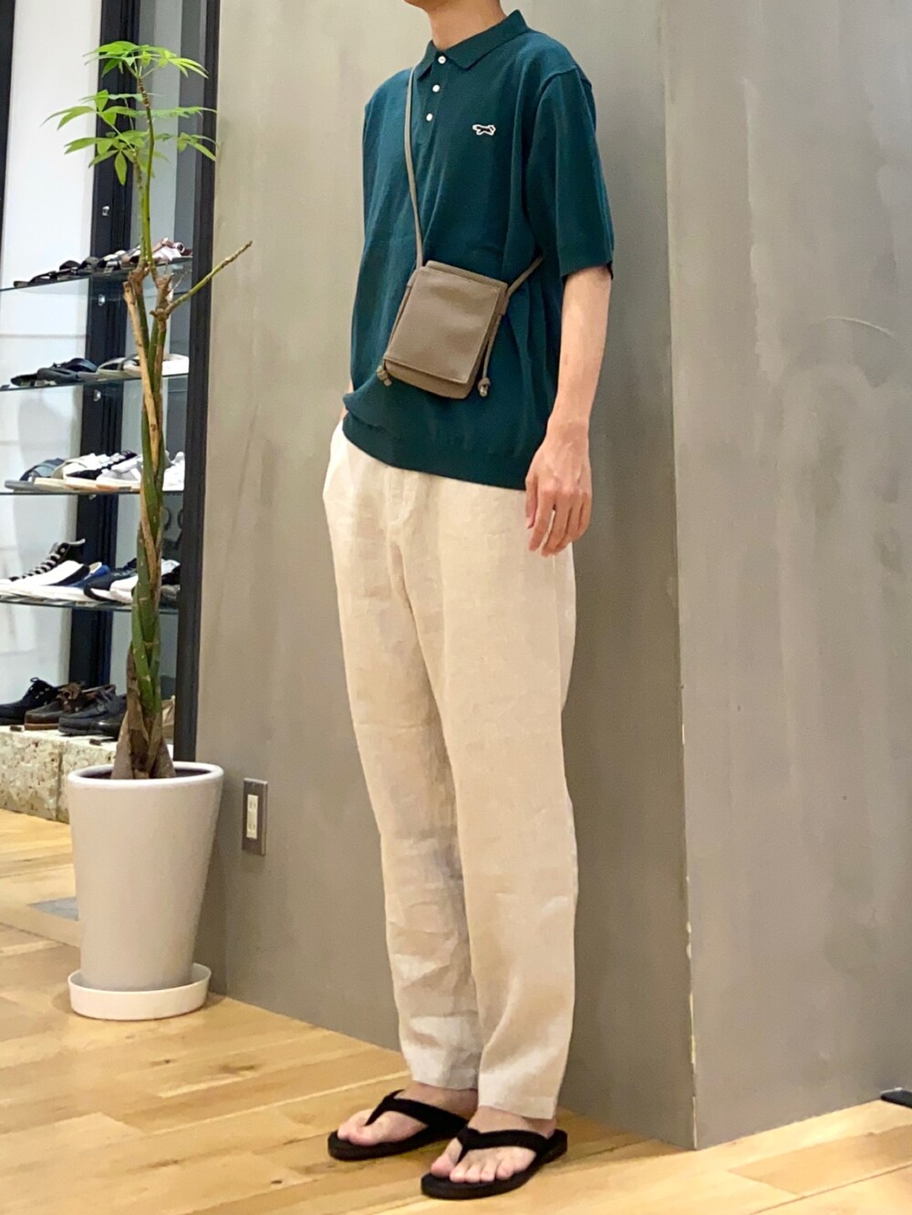 グリーン系のポロシャツ、ホワイト系のその他パンツ、ブラック系のサンダルを着用したメンズの春コーディネートの2枚目の写真