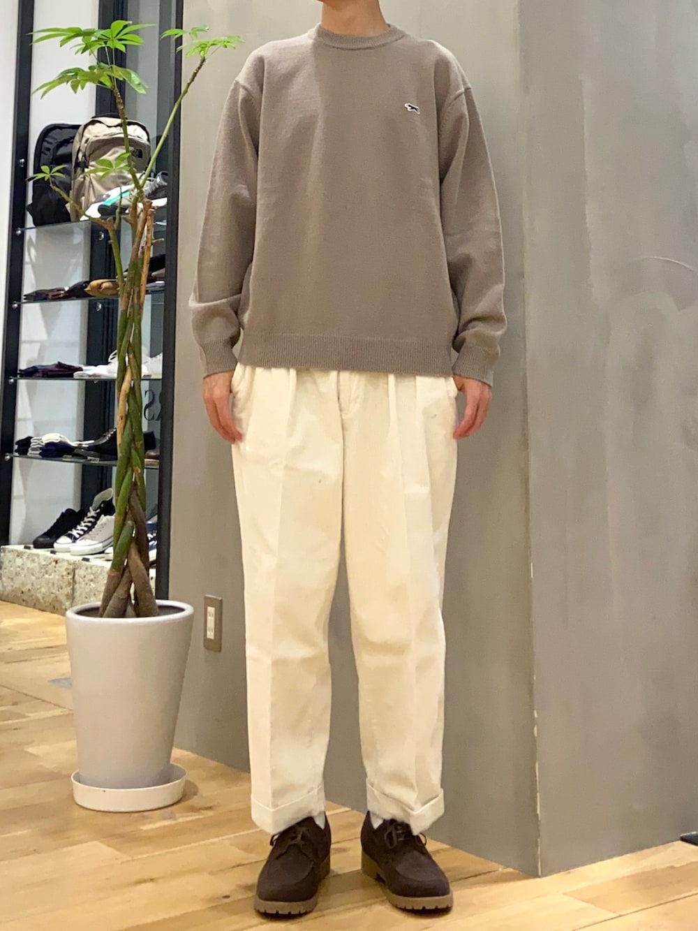 オレンジ系のステンカラーコート、ブラウン系のニット/セーター、ホワイト系のその他パンツを着用したメンズの冬コーディネートの2枚目の写真