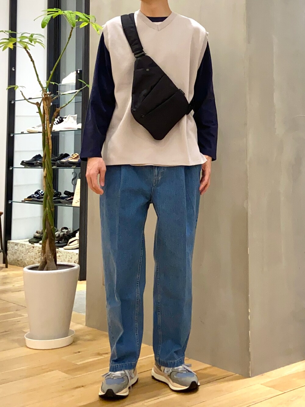 グレー系のベスト、ブルー系のTシャツ/カットソー、ブラック系のショルダーバッグを着用したメンズの春コーディネートの3枚目の写真