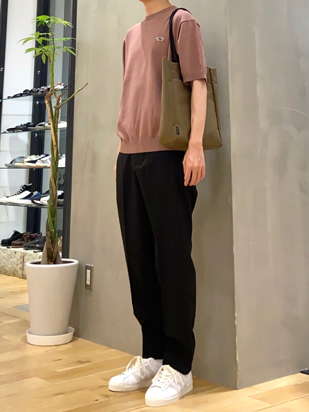 ピンク系のニット/セーター、ブラック系のその他パンツ、ブラウン系のトートバッグを着用したメンズの春コーディネートの2枚目の写真