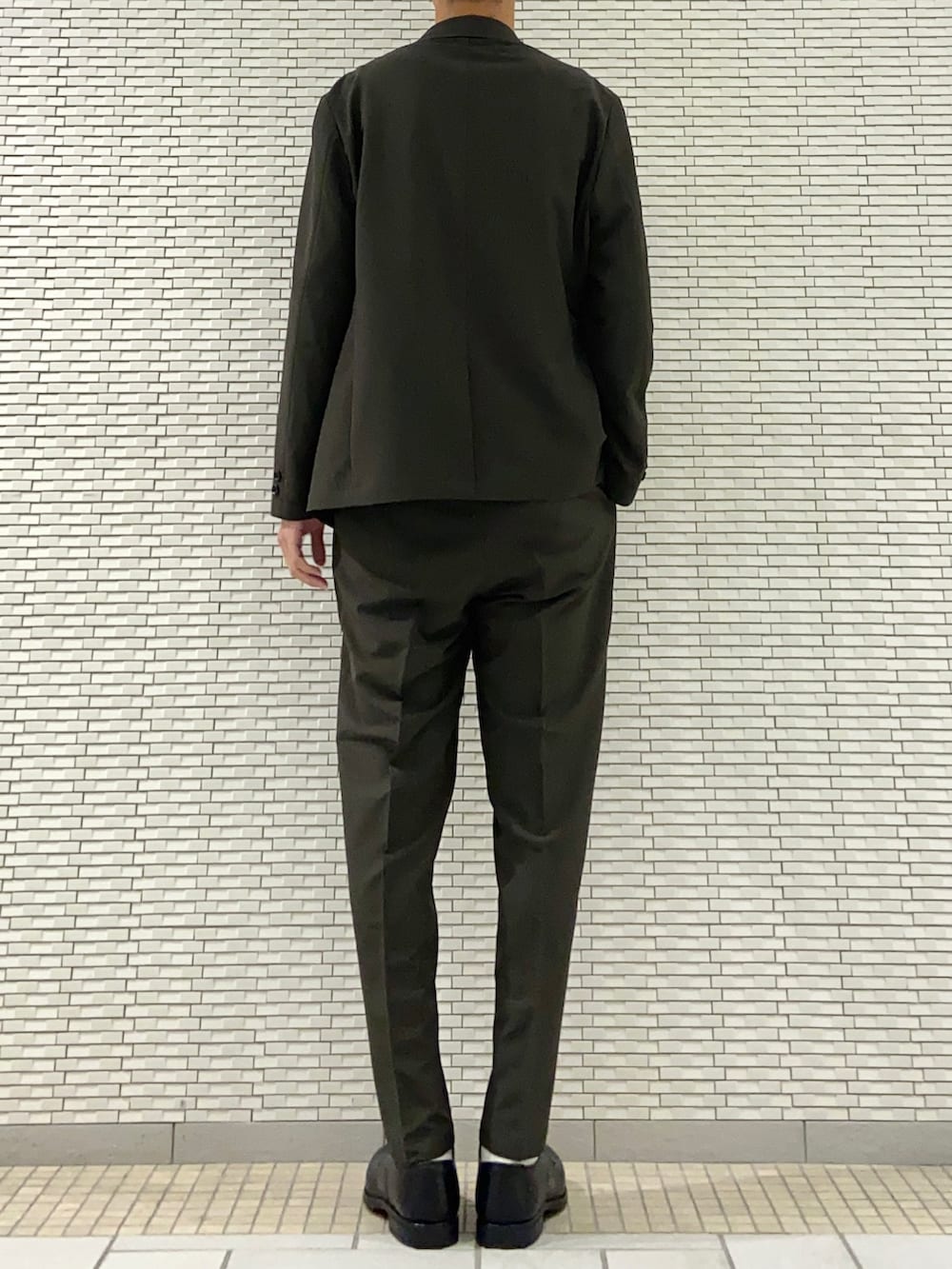 グリーン系のスーツジャケット、ブラウン系のニット/セーター、グリーン系のスーツパンツを着用したメンズの春コーディネートの3枚目の写真