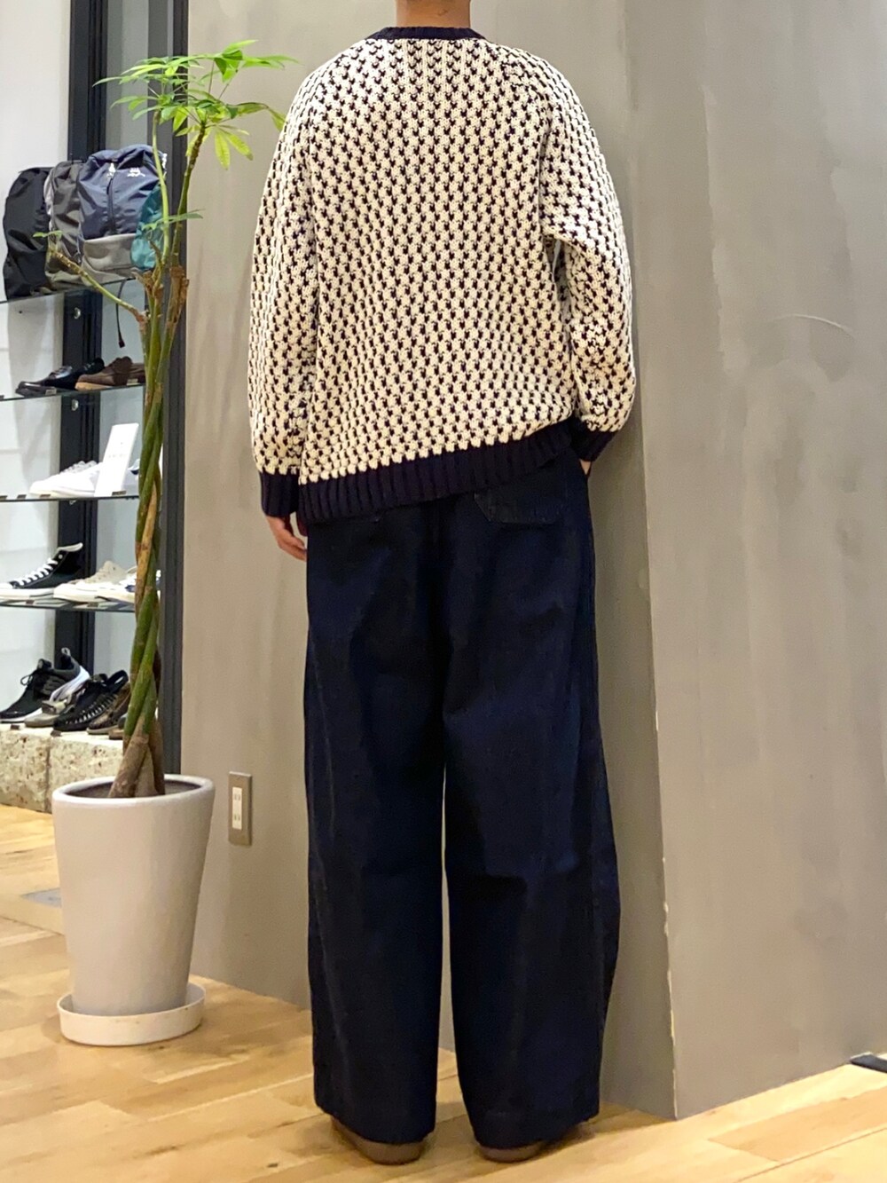 ホワイト系のニット/セーター、ブルー系のデニムパンツ、ホワイト系のスニーカーを着用したメンズの秋コーディネートの4枚目の写真