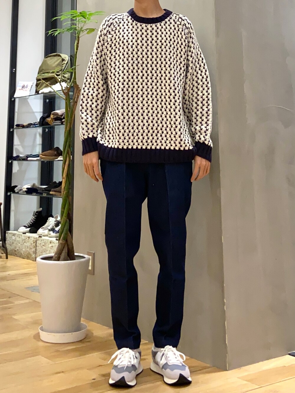 グリーン系のダウンジャケット/コート、ホワイト系のニット/セーター、ブルー系のデニムパンツを着用したメンズの秋コーディネートの2枚目の写真