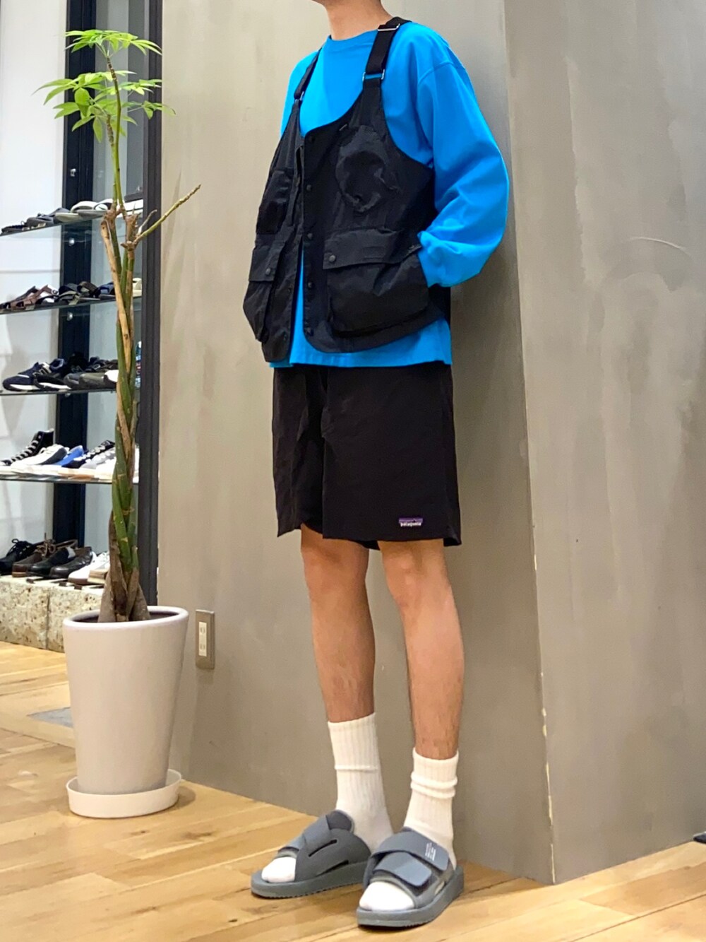 ブラック系のベスト、ブルー系のTシャツ/カットソー、グレー系のサンダルを着用したメンズの春コーディネートの2枚目の写真