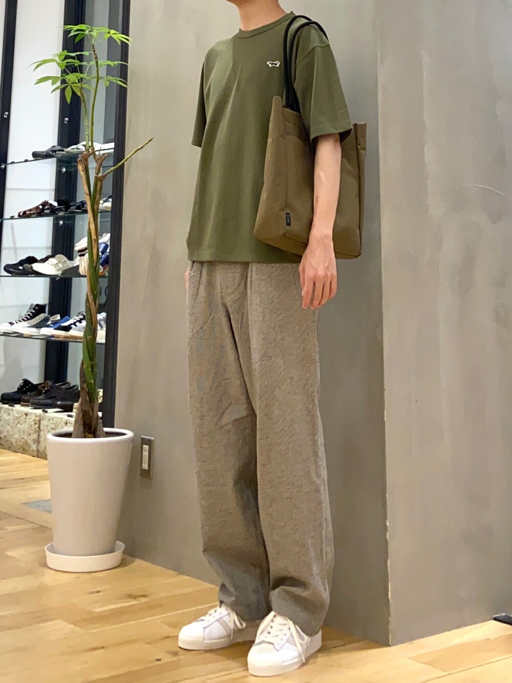 グリーン系のTシャツ/カットソー、ホワイト系のその他パンツ、ブラウン系のトートバッグを着用したメンズの春コーディネートの2枚目の写真