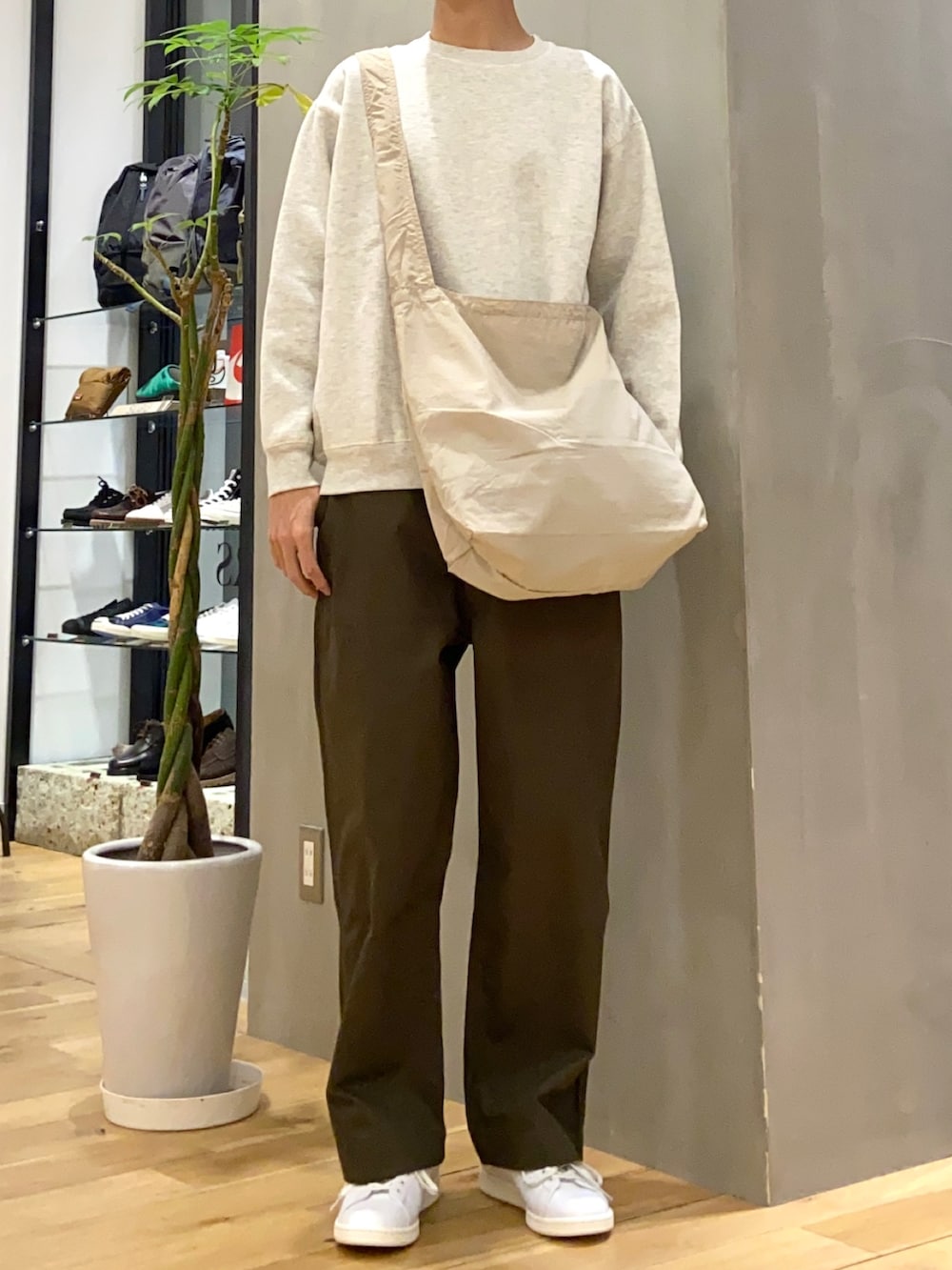 オレンジ系のステンカラーコート、ホワイト系のスウェット、グリーン系のその他パンツを着用したメンズの冬コーディネートの3枚目の写真