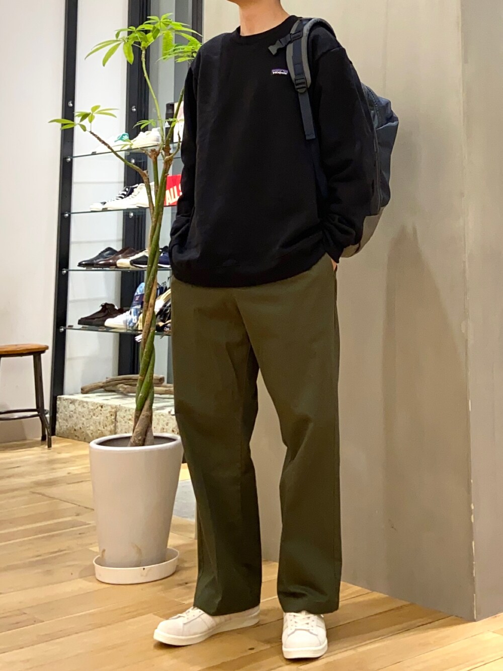 グリーン系のチノパンツ、ブルー系のバックパック/リュック、ベージュ系のスニーカーを着用したメンズの冬コーディネートの2枚目の写真