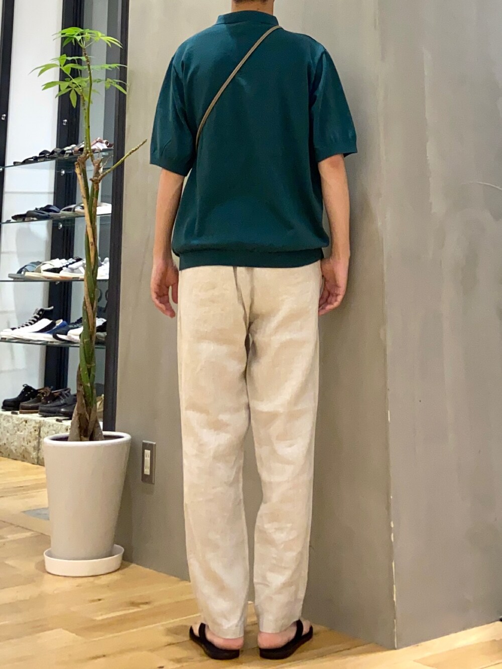 グリーン系のポロシャツ、ホワイト系のその他パンツ、ブラック系のサンダルを着用したメンズの春コーディネートの3枚目の写真