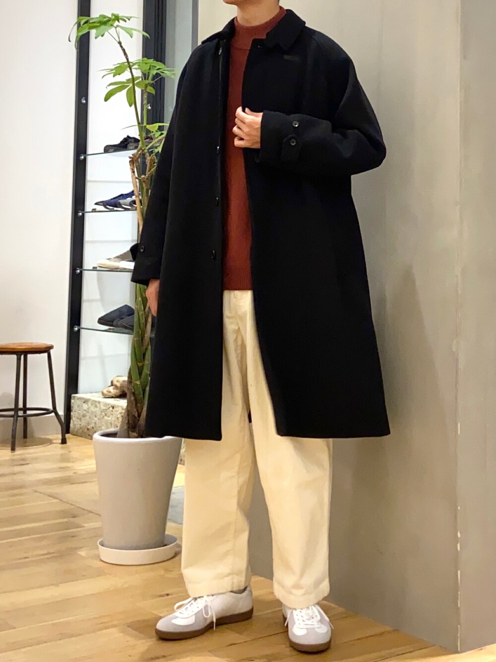 ブラック系のステンカラーコート、レッド系のニット/セーター、ホワイト系のその他パンツを着用したメンズの秋コーディネートの4枚目の写真