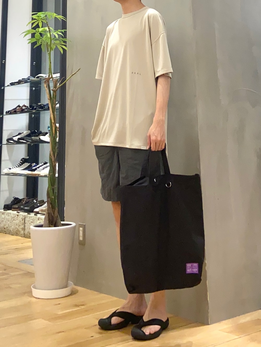 ベージュ系のTシャツ/カットソー、ブラック系のトートバッグを着用したメンズの春コーディネートの2枚目の写真