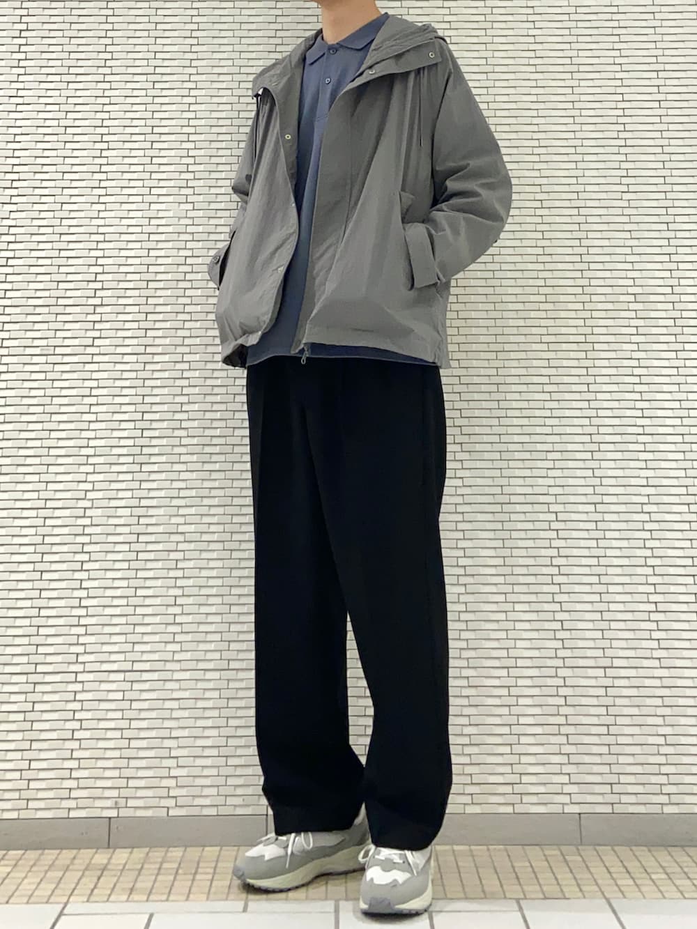 グレー系のマウンテンパーカー、ブルー系のポロシャツ、ブラック系のその他パンツを着用したメンズの春コーディネートの3枚目の写真