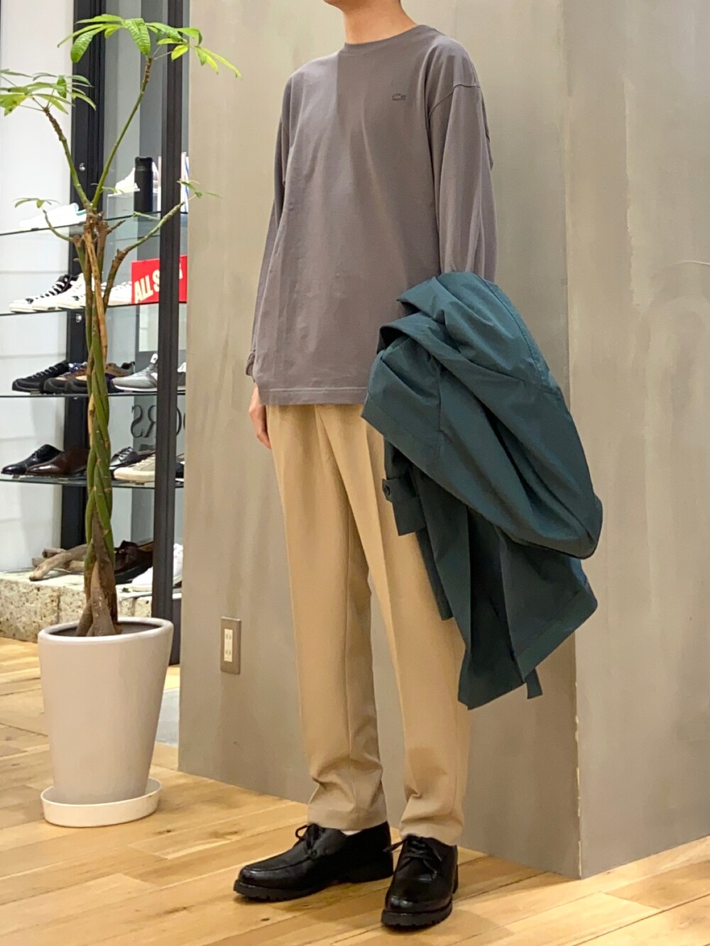 グリーン系のステンカラーコート、グレー系のTシャツ/カットソー、ベージュ系のその他パンツを着用したメンズの春コーディネートの4枚目の写真