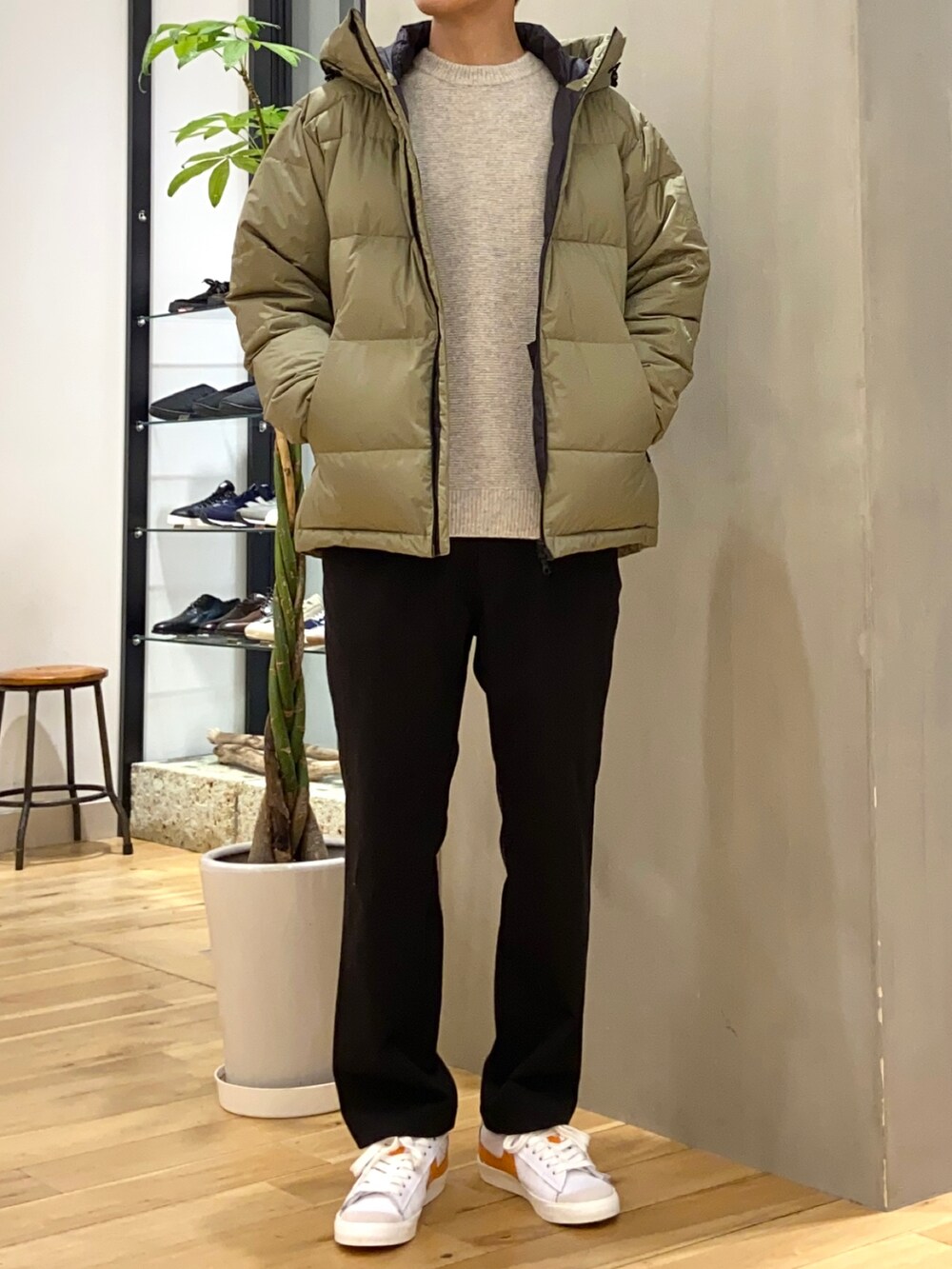 グリーン系のダウンジャケット/コート、ベージュ系のニット/セーター、オレンジ系のスニーカーを着用したメンズの冬コーディネートの3枚目の写真