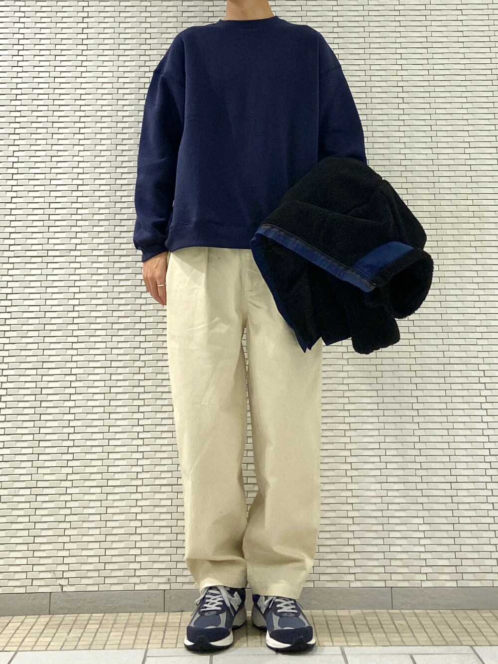 ブラック系のブルゾン、ホワイト系のチノパンツ、ブルー系のスニーカーを着用したメンズの秋コーディネートの3枚目の写真