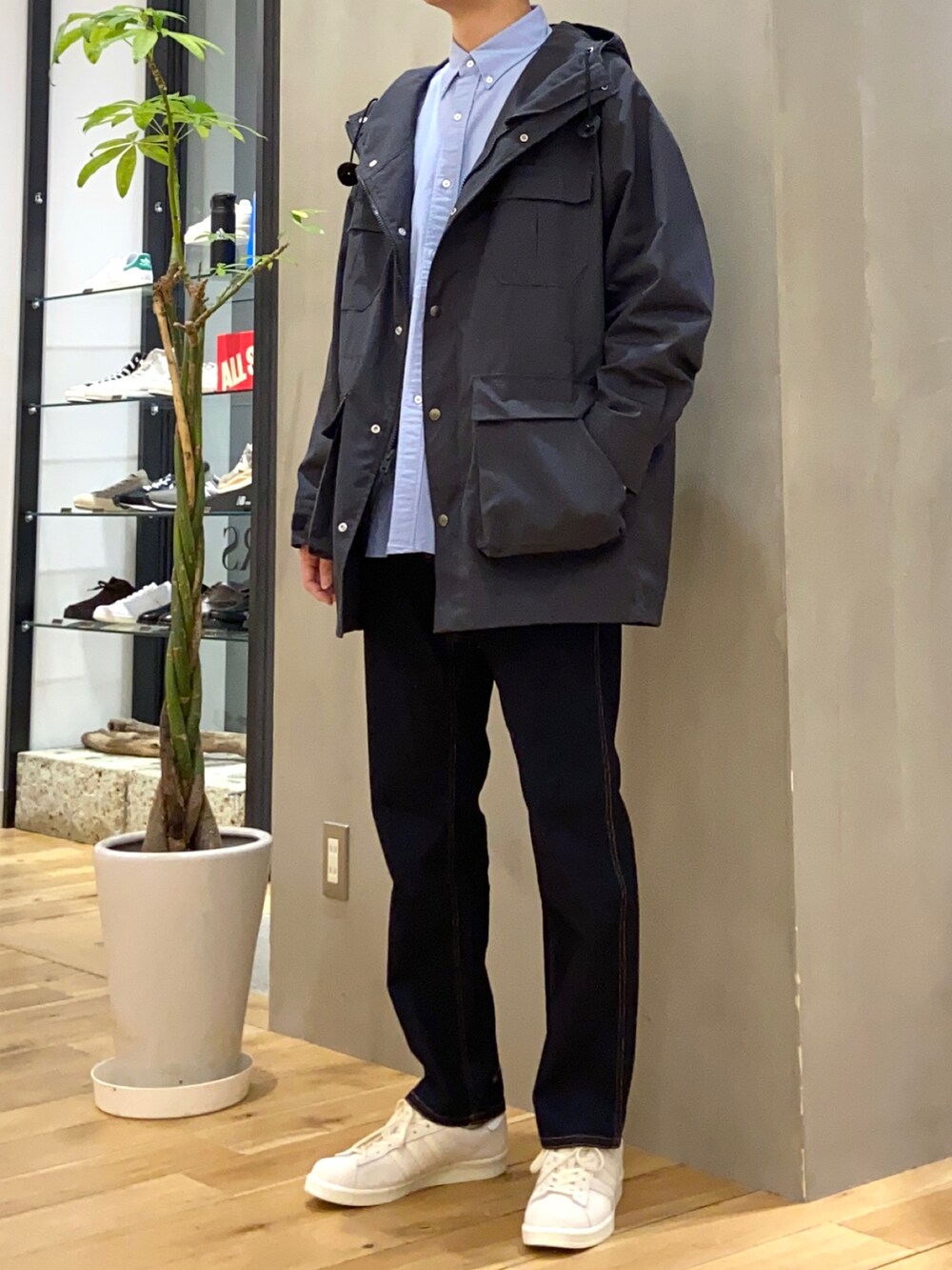 ブラック系のマウンテンパーカー、ブルー系のシャツ/ブラウス、ベージュ系のスニーカーを着用したメンズの春コーディネートの2枚目の写真