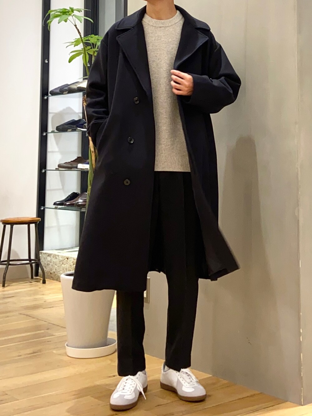 ブルー系のチェスターコート、ベージュ系のニット/セーター、グレー系のその他パンツを着用したメンズの冬コーディネートの3枚目の写真