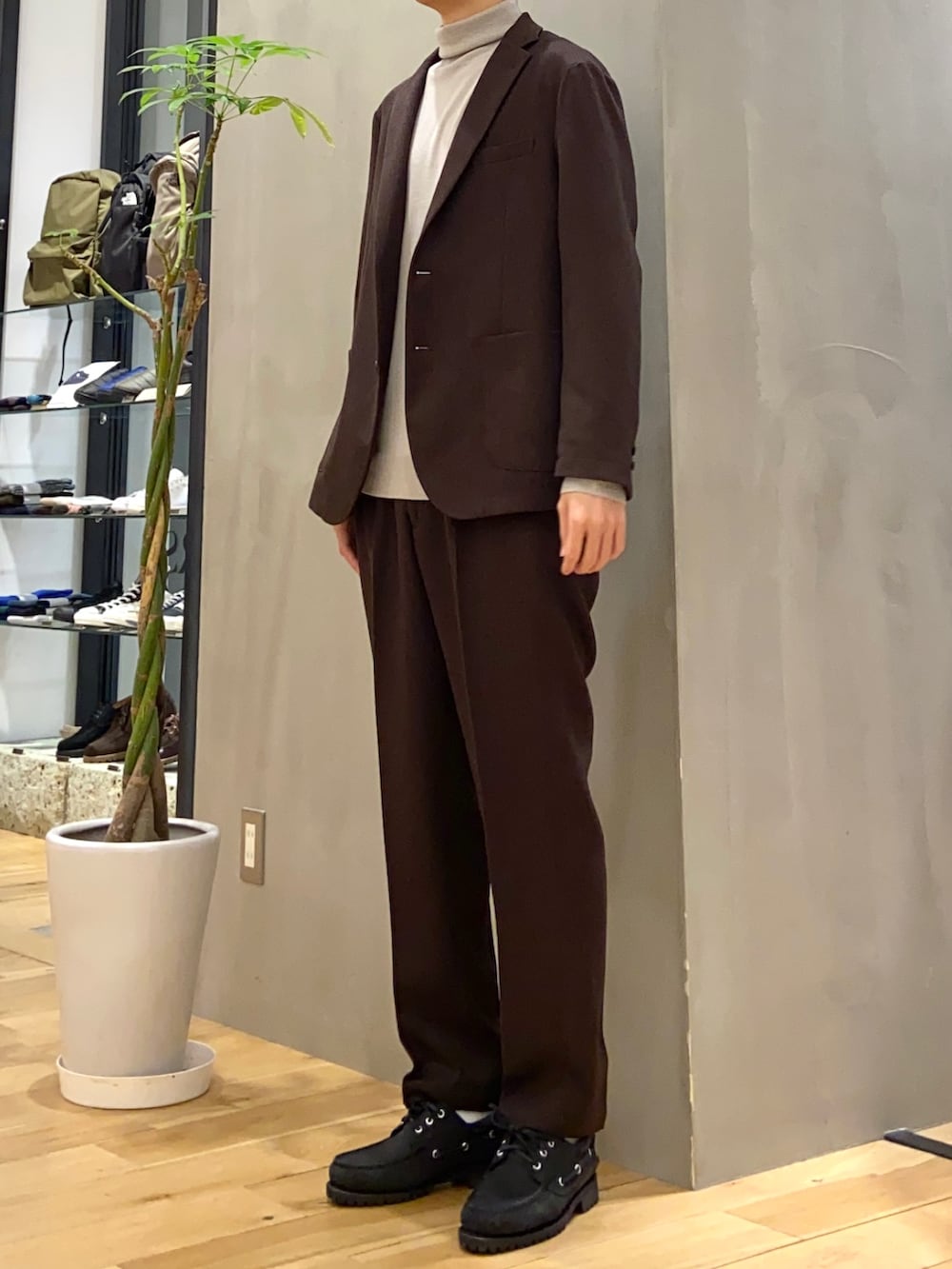 ブラウン系のその他アウター、ベージュ系のニット/セーター、ブラウン系のスーツパンツを着用したメンズの冬コーディネートの3枚目の写真