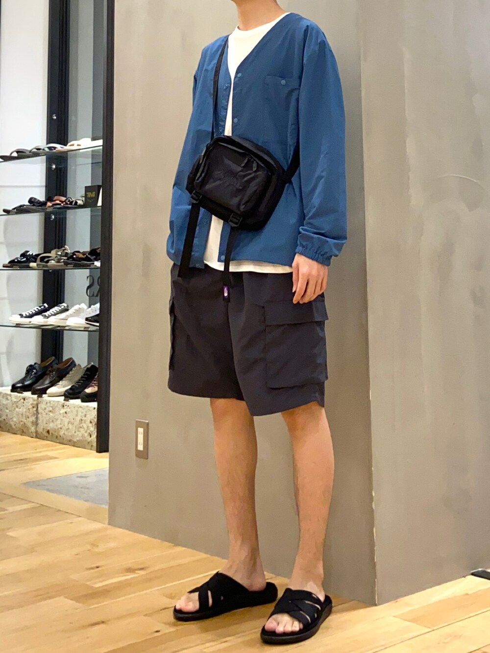 ブルー系のナイロンジャケット、グレー系のその他パンツ、ブラック系のサンダルを着用したメンズの春コーディネートの2枚目の写真
