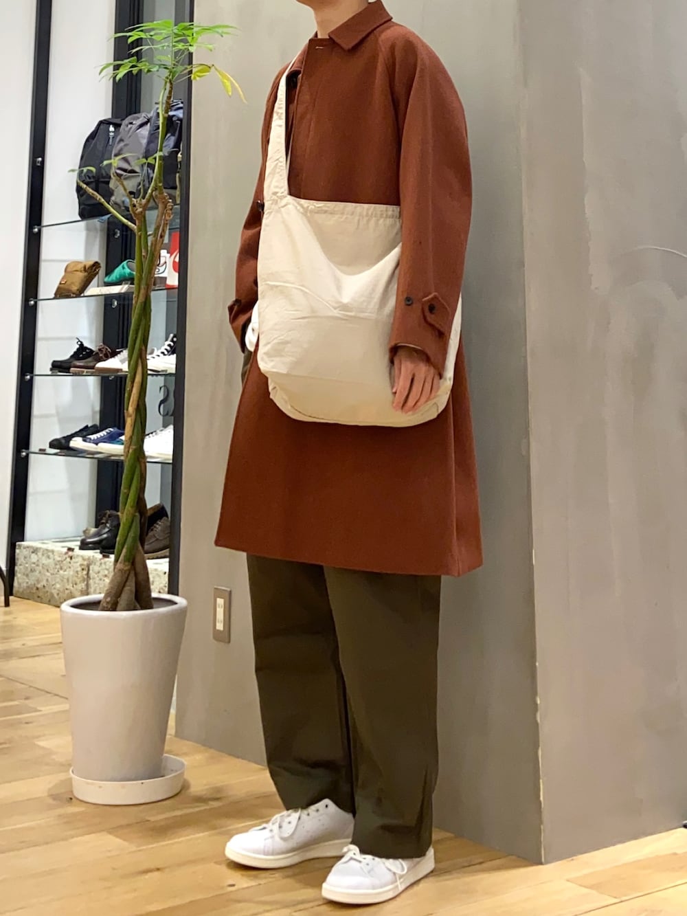 オレンジ系のステンカラーコート、ホワイト系のスウェット、グリーン系のその他パンツを着用したメンズの冬コーディネートの4枚目の写真