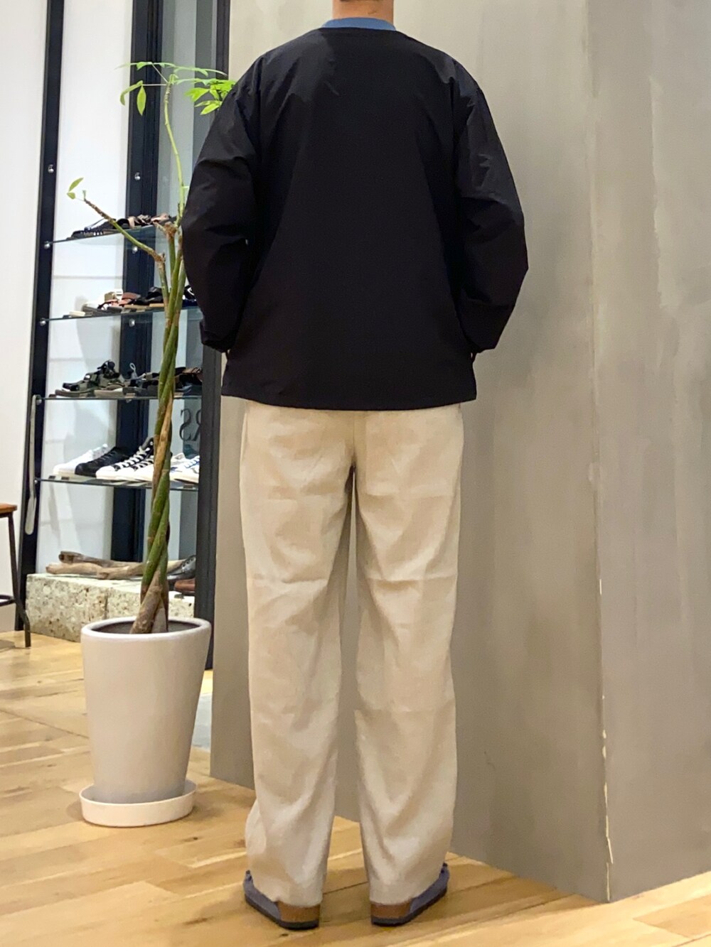 ブラック系のブルゾン、ベージュ系のその他パンツ、ブルー系のサンダルを着用したメンズの夏コーディネートの4枚目の写真