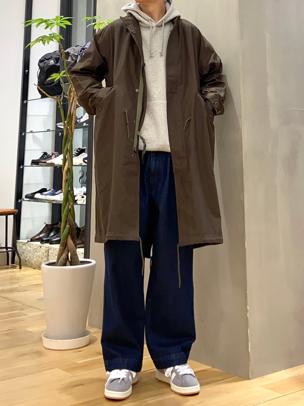 グレー系のパーカー、グリーン系のモッズコート、ブルー系のデニムパンツを着用したメンズの冬コーディネートの4枚目の写真