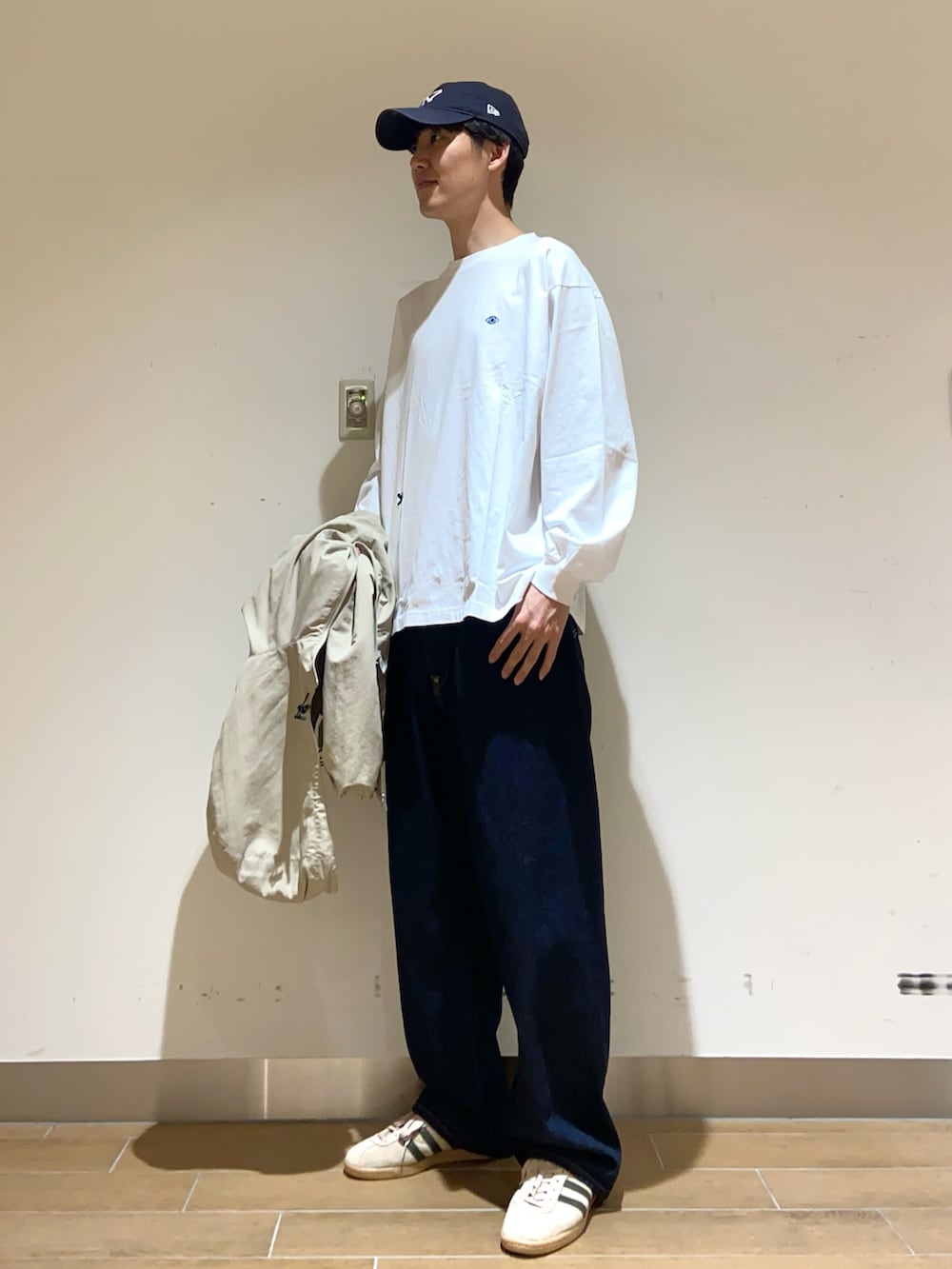 ベージュ系のマウンテンパーカー、ホワイト系のTシャツ/カットソー、ブルー系のデニムパンツを着用したメンズの春コーディネートの2枚目の写真