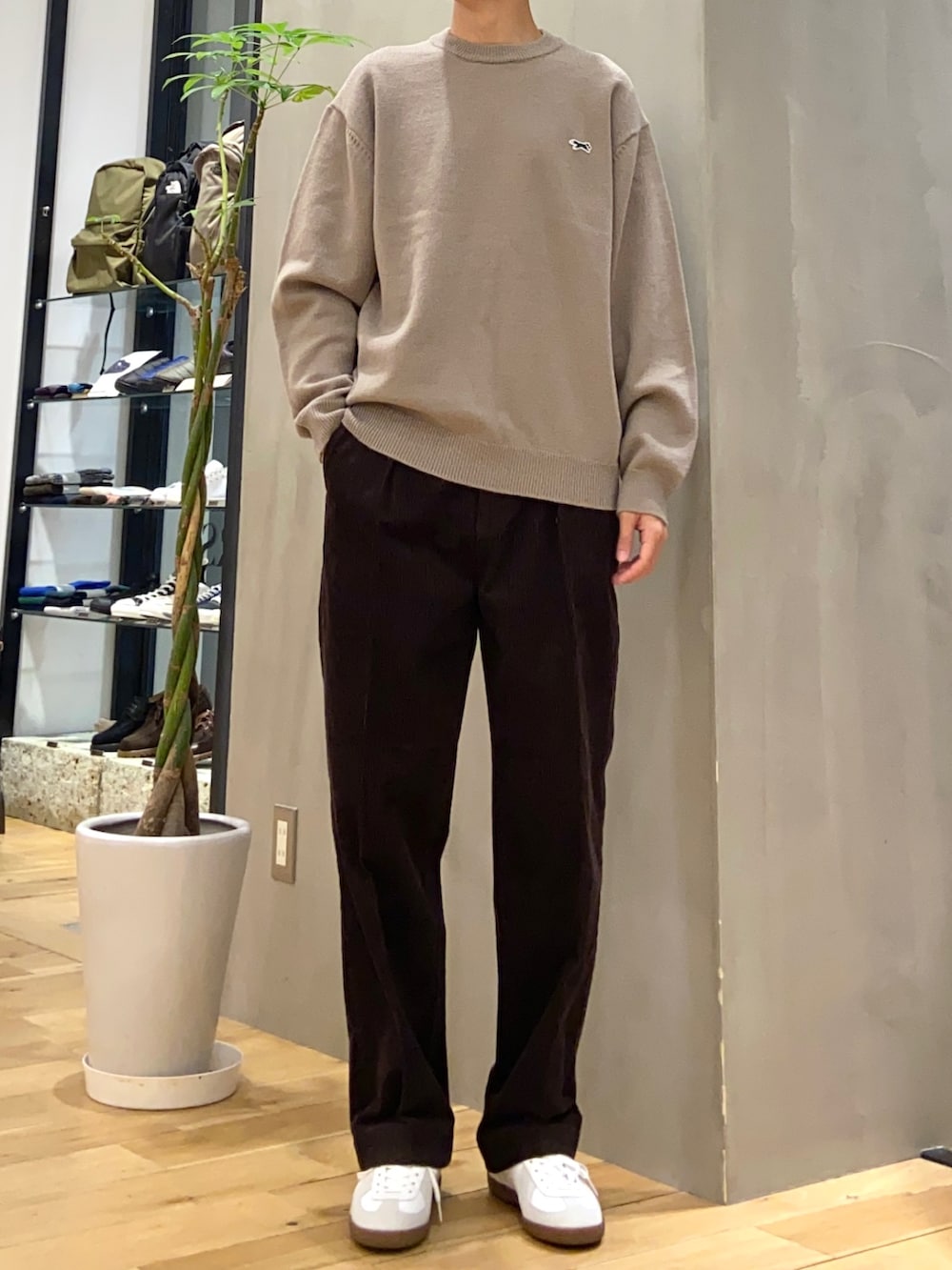 グレー系のダウンジャケット/コート、ブラウン系のニット/セーター、ホワイト系のスニーカーを着用したメンズの冬コーディネートの2枚目の写真