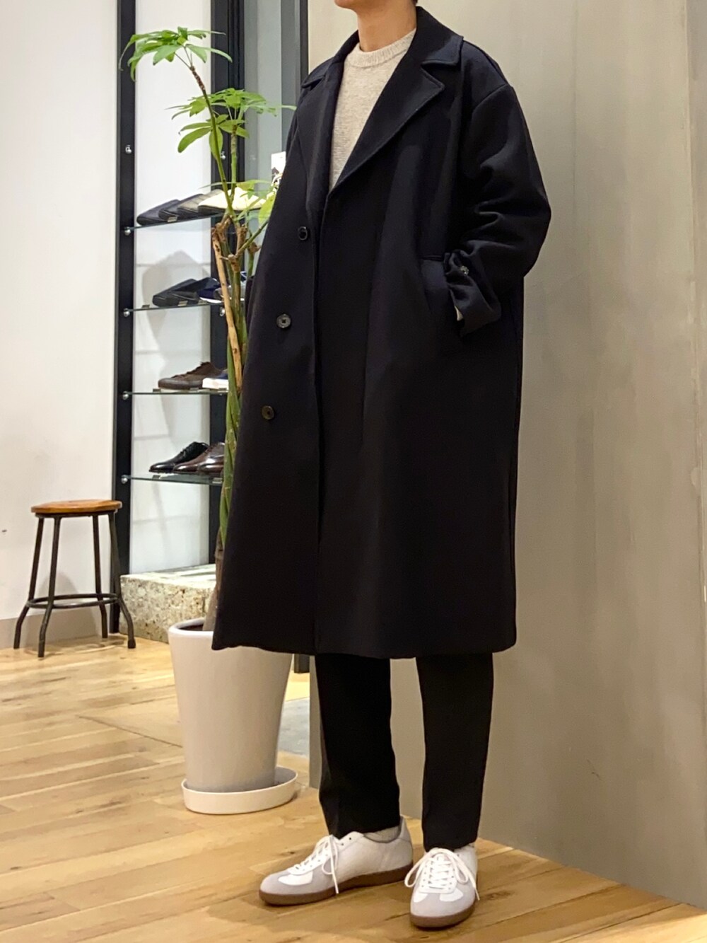 ブルー系のチェスターコート、ベージュ系のニット/セーター、グレー系のその他パンツを着用したメンズの冬コーディネートの2枚目の写真