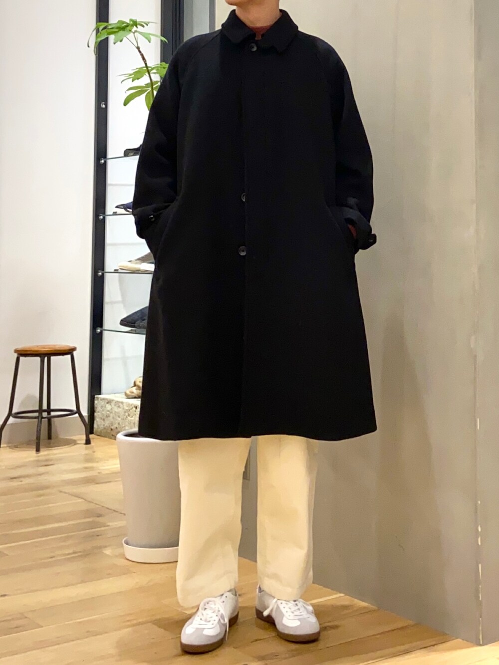 ブラック系のステンカラーコート、レッド系のニット/セーター、ホワイト系のその他パンツを着用したメンズの秋コーディネートの5枚目の写真