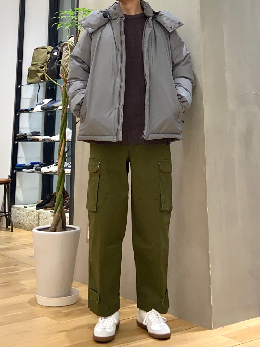 グレー系のダウンジャケット/コート、グレー系のニット/セーター、ホワイト系のスニーカーを着用したメンズの冬コーディネートの3枚目の写真