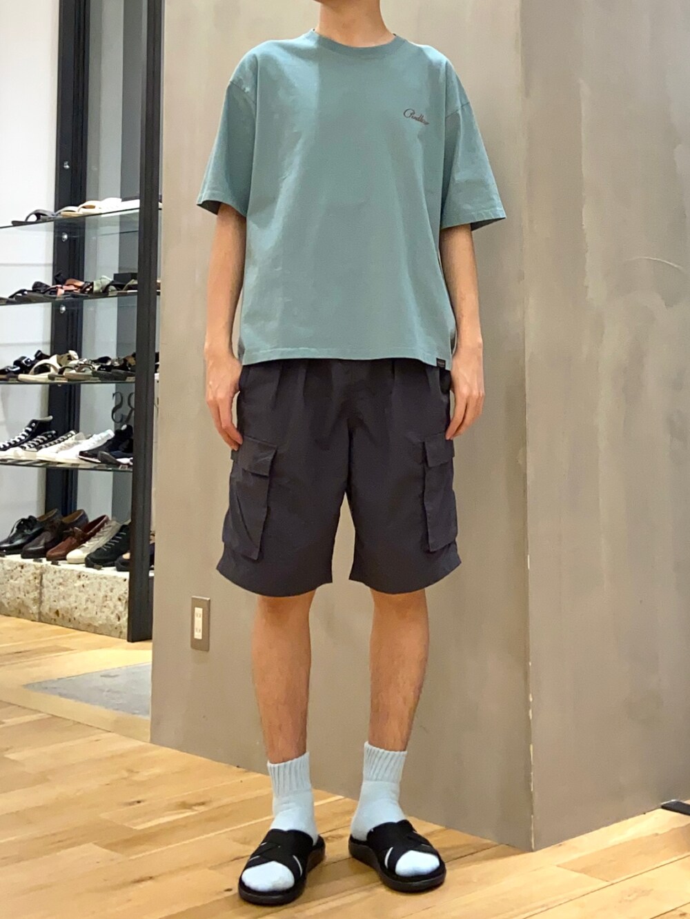 グリーン系のTシャツ/カットソー、グレー系のその他パンツ、ブラック系のサンダルを着用したメンズの春コーディネートの2枚目の写真