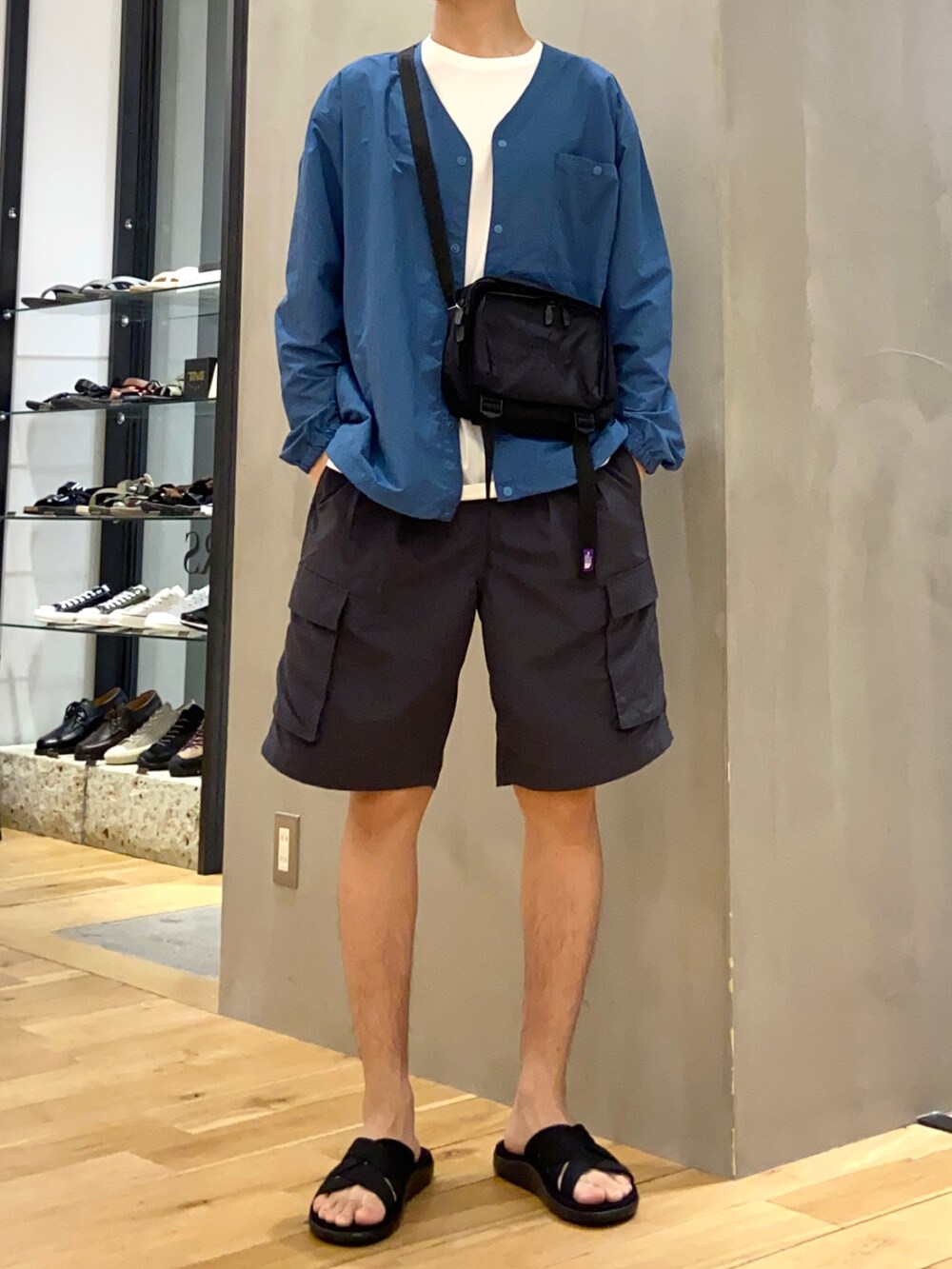 ブルー系のナイロンジャケット、グレー系のその他パンツ、ブラック系のサンダルを着用したメンズの春コーディネートの3枚目の写真