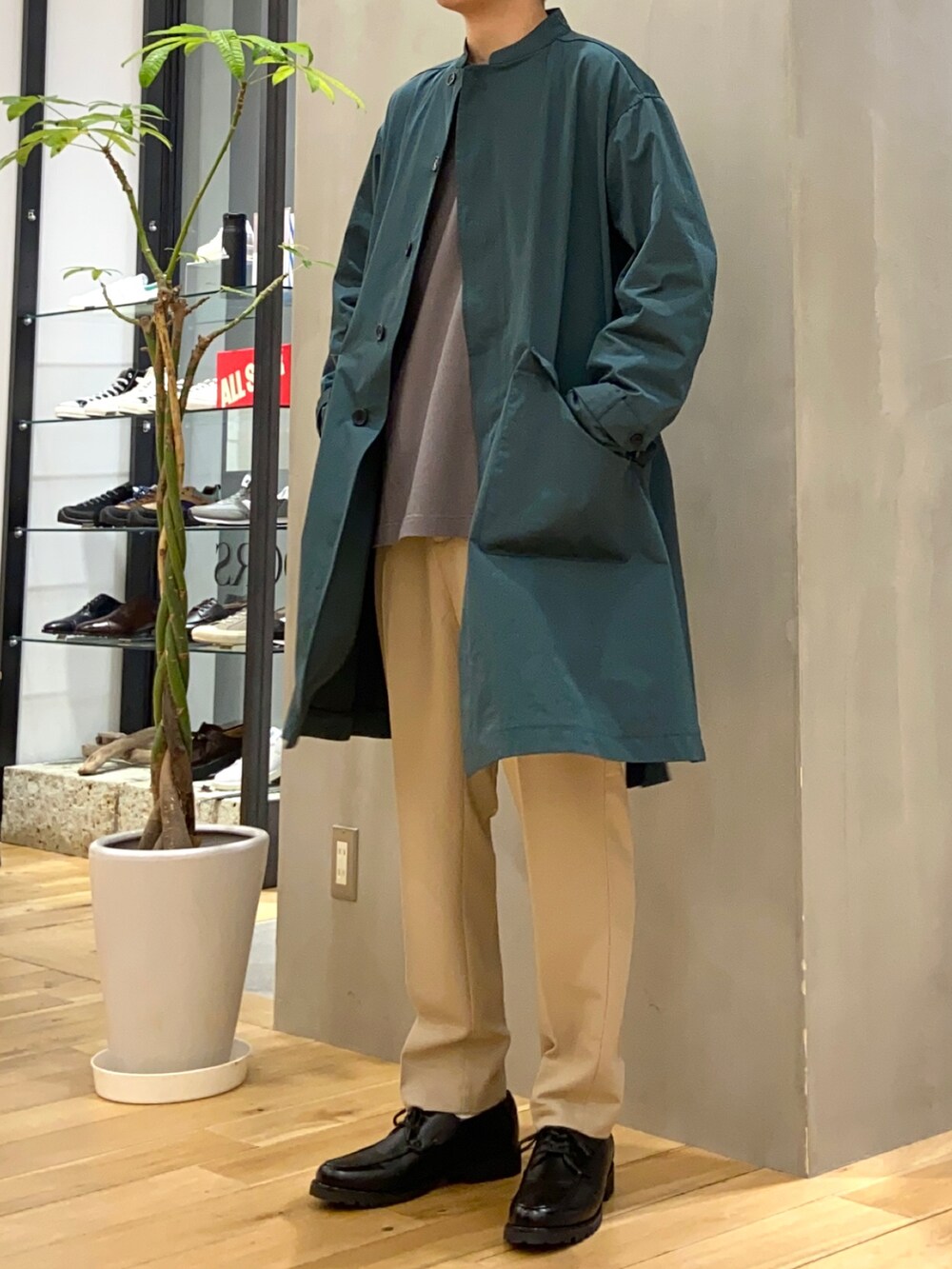 グリーン系のステンカラーコート、グレー系のTシャツ/カットソー、ベージュ系のその他パンツを着用したメンズの春コーディネートの3枚目の写真