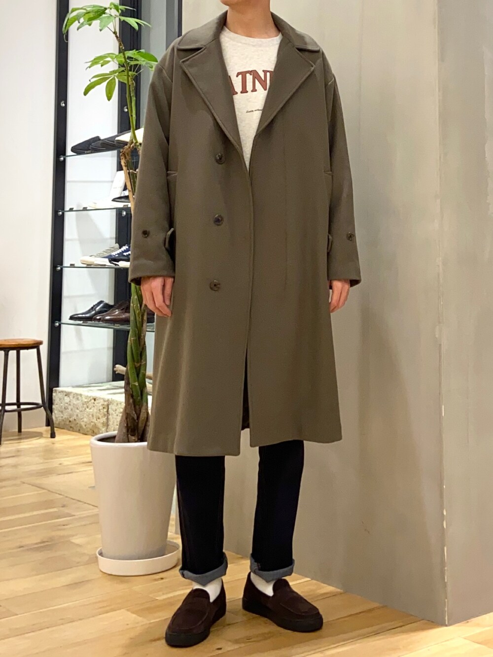 ベージュ系のチェスターコート、ホワイト系のスウェット、ブラウン系のローファーを着用したメンズの冬コーディネートの3枚目の写真