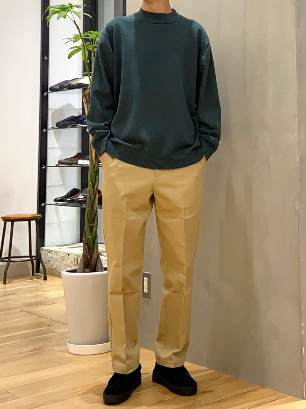 ブラック系のステンカラーコート、グリーン系のニット/セーター、ベージュ系のその他パンツを着用したメンズの冬コーディネートの2枚目の写真